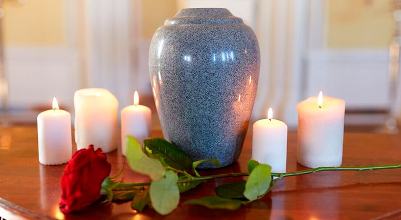 Urna de cremación con velas y una flor
